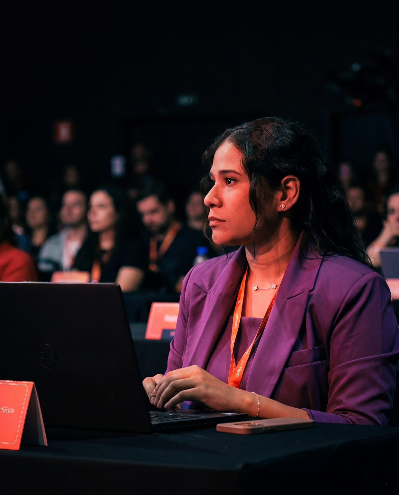 Ariela Felícia em um evento de marketing, de blazer roxo, diante do notebook